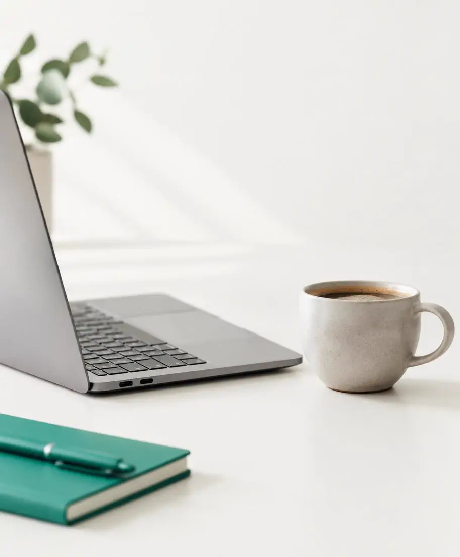 Ordinateur portable ouvert vu de côté, écran non visible, et tasse de café